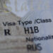 Fragment of H1B visa (for specialty workers) stamp in passport, blurred april calendar on background. H1B visa program dea...