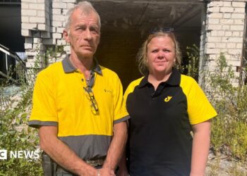 Igor Smelyansky stands in his blue Ukrposhta shirt and smiles at the camera. He has greying dark hair, and wears stubble with a smile