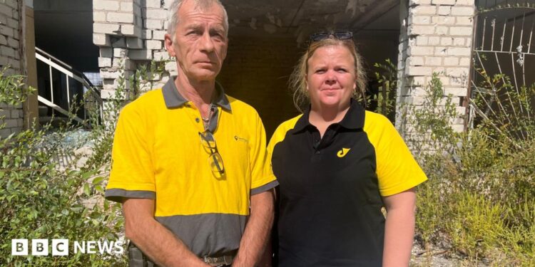Igor Smelyansky stands in his blue Ukrposhta shirt and smiles at the camera. He has greying dark hair, and wears stubble with a smile