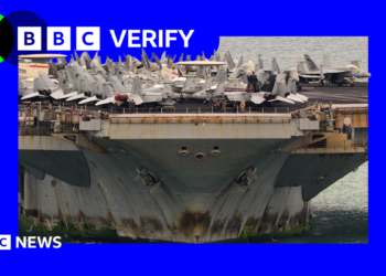 A photo of the the bottom half of the USS Lincoln with rust and algae on it, with war planes on top of the deck.