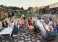 Community members raise their arms during a gratitude poem at a supper in Westbrook, Maine, in July 2025 [Courtesy of Community Plate]