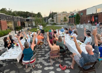 Community members raise their arms during a gratitude poem at a supper in Westbrook, Maine, in July 2025 [Courtesy of Community Plate]