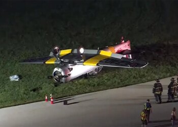 first responders stand near the overturned aircraft